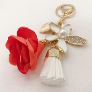 Detail of red fabric rose keychain with pearl rhinestone flower and white tassel accent