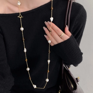 Elegant tiger eye and baroque pearl long necklace with golden T-bar clasp on black sweater