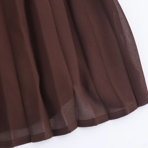 Detailed close-up showing the pleated chiffon fabric and hemline of the brown midi dress