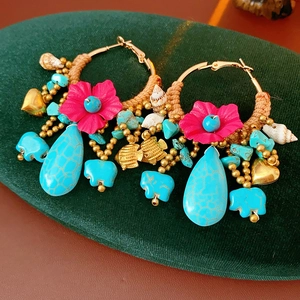 Detail of bohemian earrings featuring pink flowers, turquoise elephant beads and shells