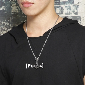 Close-up of Viking Thor Hammer pendant on twisted chain worn with punk style streetwear
