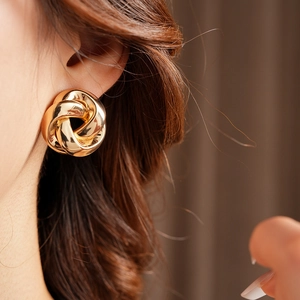 Gros plan de boucles d'oreilles nœud dorées élégantes portées par un mannequin