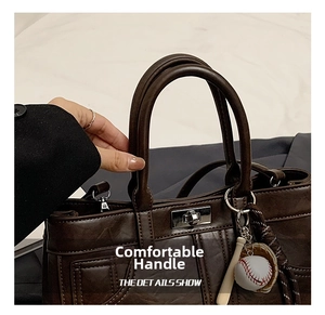 Détail d'un sac à main vintage en cuir marron avec fermoir métallique et breloque baseball