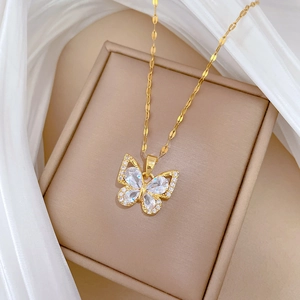 Macro detail of gold butterfly necklace with zircon inlay on a jewelry gift box