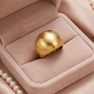 Close-up of a wide gold matte stainless steel ring inside a pink velvet jewelry box