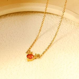 Exquisite golden elk necklace with a central red zircon pendant on a textured surface