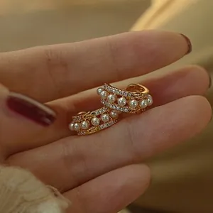 Detailed view of gold-tone pearl hoop earrings with rows of fine pavé crystals