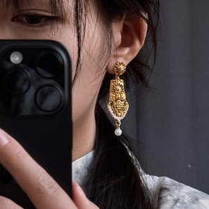 Close-up of vintage geometric hollow pearl earrings worn by a model in natural light