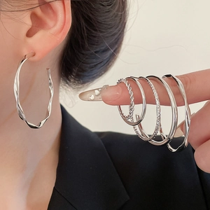 Close-up of twisted silver hoop earrings showing metallic texture on a model