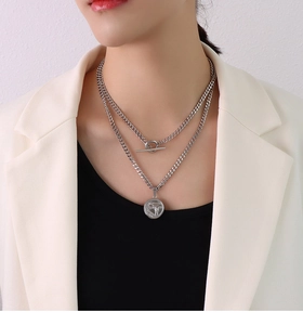Detail of silver double layer necklace with thick chain, OT buckle and round gun pendant