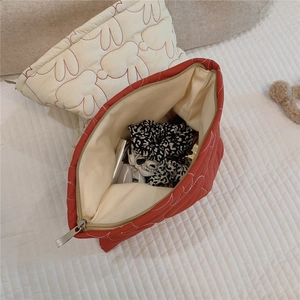 Detailed view of quilted makeup bags with cute rabbit patterns and red fabric texture