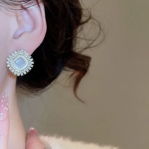 Close-up of a vintage square opal stud earring with micro-diamonds on a model