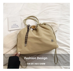 Detail of drawstring nylon tote bag with floral metal logo and sports charm on bed