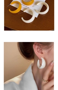 Close-up of retro C-shaped thick acrylic hoop earrings in yellow and cream white