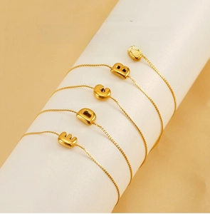 Macro detail of 18K gold plated stainless steel initial bracelets on a jewelry stand