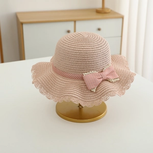 Close-up of pink straw hat with wave lace edge and polka dot bow on a display stand