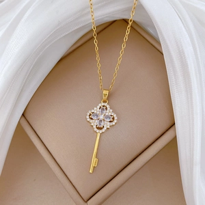Detail of clover key pendant with crystals on gold titanium steel necklace