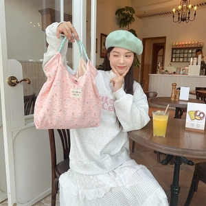 Detailed shot of pink canvas tote bag with rabbit print and blue checkered handles