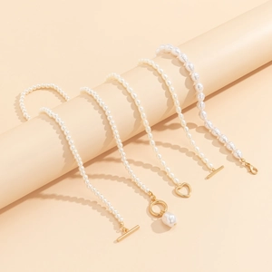 Detailed view of assorted white pearl necklaces with golden OT clasps and heart charms
