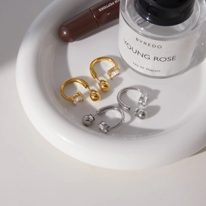 U-shaped gold and silver stainless steel earrings with zircon stones on a white tray