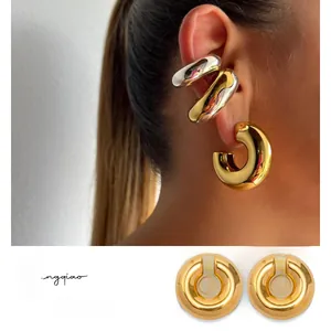 Gros plan de boucles d'oreilles chunky en forme de C or et argent sur une oreille