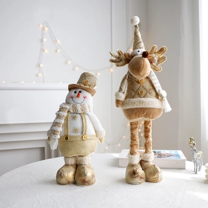 Detail of plush Christmas snowman and reindeer dolls with golden knits on a table