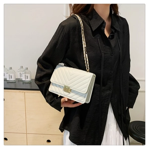 Detail of white quilted PU leather crossbody bag with gold chain and metal lock
