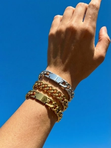 Close-up of stacked gold and silver cuban link bracelets with engravable metal plate