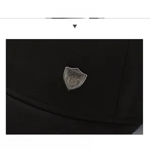 Close-up of black baseball cap with silver metal shield emblem and fine fabric texture