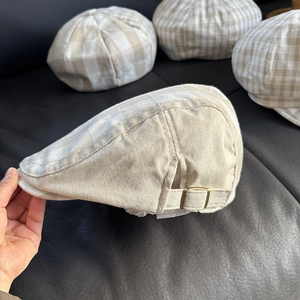 Detail of adjustable metal buckle and linen texture on a beige flat ivy cap