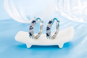 Close-up of silver hoop earrings with alternating blue and clear inlaid crystals