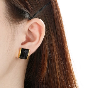 Close-up of square black faceted gemstone earrings with 18K gold-plated borders