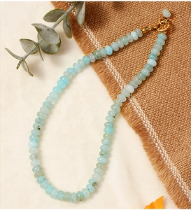 Close-up of aquamarine crystal beads and gold metal buckle on a textured fabric