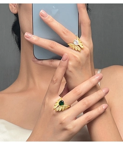 Close-up of elegant gold butterfly rings with white and green stones on hand