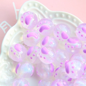 Vue macro de perles transparentes de 16mm avec empreintes de pattes violettes et paillettes
