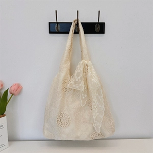 Detail of floral embroidery on beige lace tote bag with silk ribbon bow and tulip accent