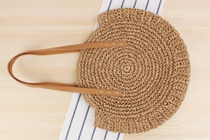 Detailed top view of round woven paper rope shoulder bag on wooden surface