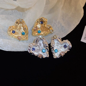 Detailed macro view of heart-shaped earrings with lava texture and colorful rhinestones