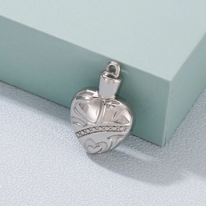 Vintage stainless steel heart locket necklace with intricate engraved patterns on blue block