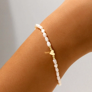 Dettaglio del ciondolo a cuore in oro 18K su un bracciale di perle barocche bianche