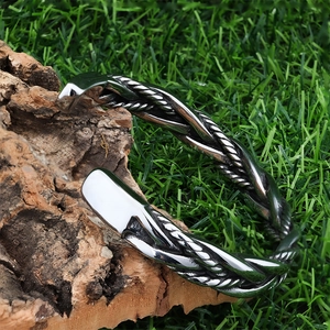Macro detail of silver vintage braided stainless steel cuff bracelet on wood