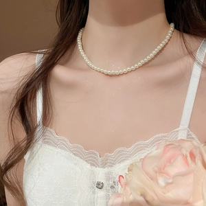 Close-up of minimalist pearl necklace on model's collarbone with white lace top