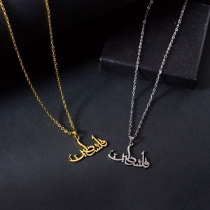 Gros plan de colliers en or et argent avec calligraphie arabe dans un coffret cadeau