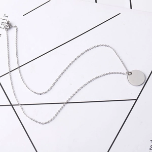 Macro detail of polished stainless steel round disk pendant on a delicate O-link chain
