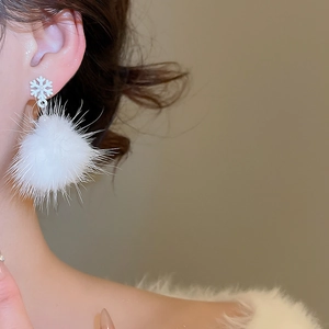 Dettaglio dell'orecchino a fiocco di neve bianco con pompon soffice su modella