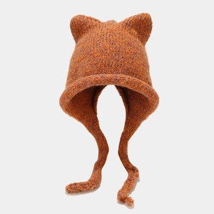 Detail of chunky knit winter hat featuring cat ears and warm caramel orange yarn texture