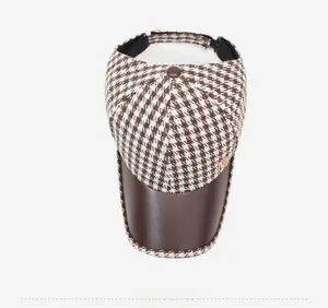 Top view of houndstooth sun visor with leather brim and golden metal logo detail