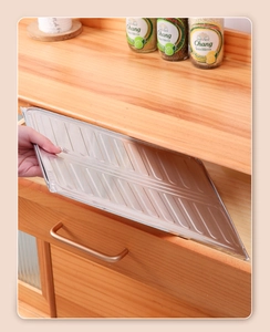 Placing a textured silver aluminum foil liner into a wooden kitchen drawer for protection