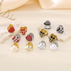 Close-up of heart-shaped enamel earrings with checkerboard patterns and rhinestones