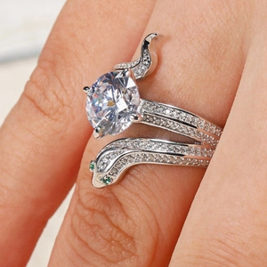 Sparkling snake-shaped ring with a large zircon center stone and green gem eyes on finger